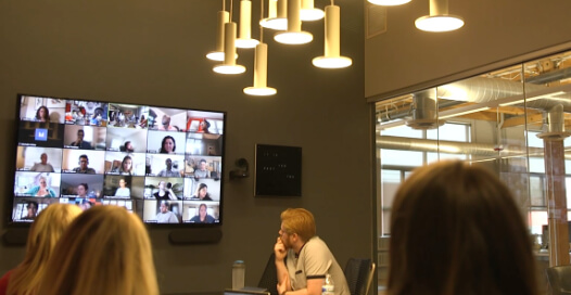 A Rocket55 Team Meeting brings together members in-office and remotely via a video meeting